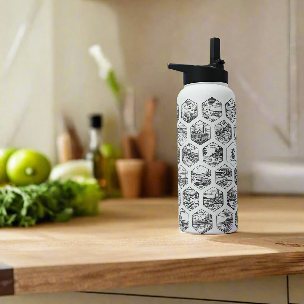 Person holding a white water bottle with black geometric pattern at a sports event.