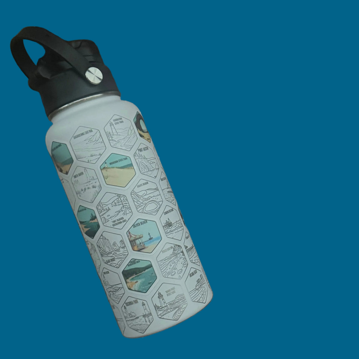 A reusable insulated water bottle with a black handle and a white body printed with a repeating hexagon pattern, resting on a dark brown wooden slat bench.